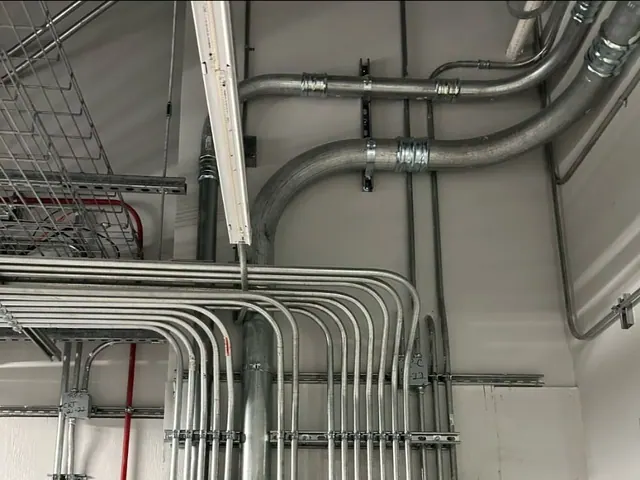 A bank of parallel conduits bent and racked into two commercial panelboards